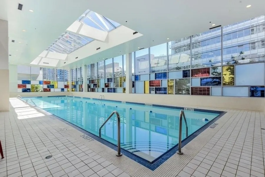 Relaxing indoor swimming pool at Orca Realty Inc. office building, featuring large windows, natural light, and modern design, ideal for health and wellness.