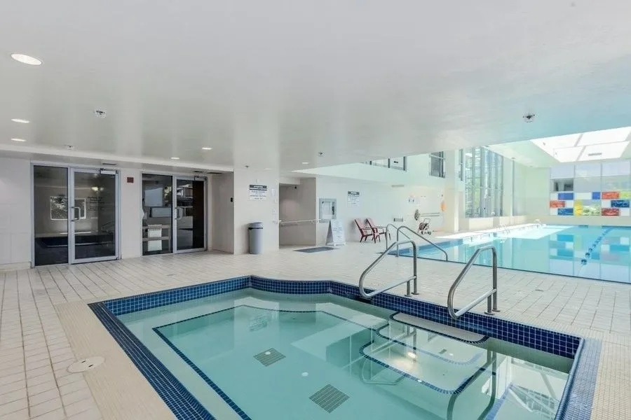 Luxurious indoor swimming pool with hot tub and modern amenities at Orca Realty Inc. property, showcasing a relaxing and upscale environment for residents and guests.