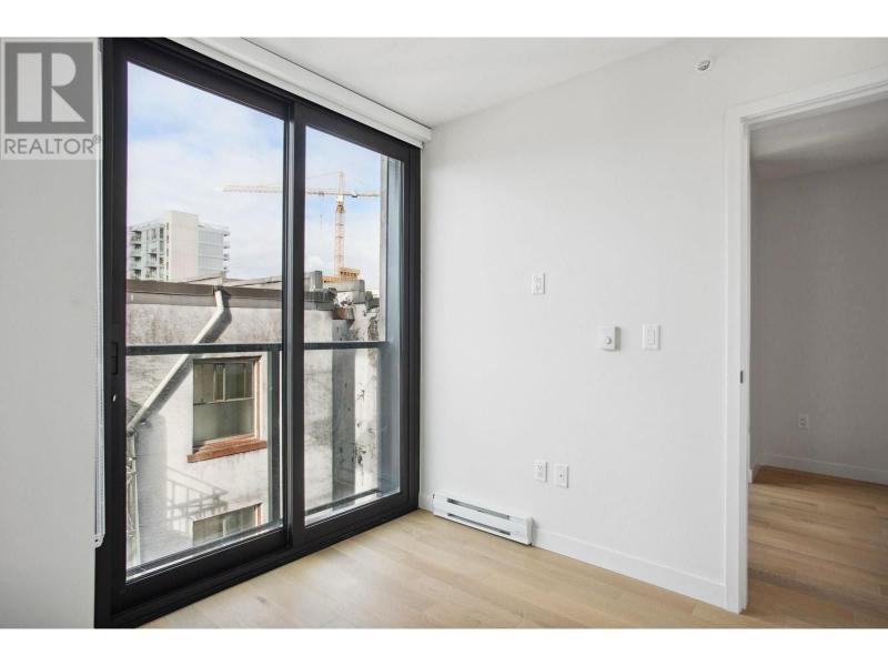 Bright interior of a Vancouver apartment with large sliding glass doors leading to a balcony, showcasing city views and natural light.