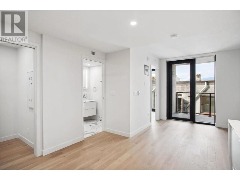 Bright, modern condo interior in Vancouver with large glass doors and hardwood floors, showcasing a spacious living area.