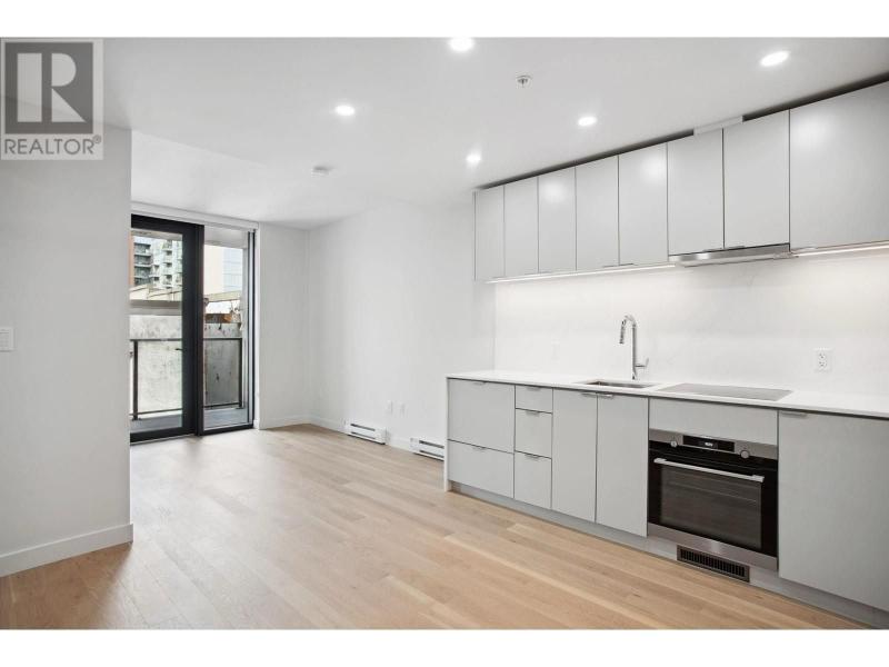 Contemporary kitchen in Vancouver condo with white cabinets, built-in oven, and balcony access, ideal for urban living.