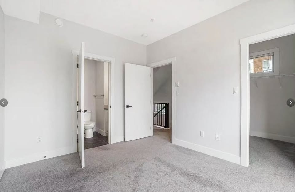 Spacious room in a modern home at 105-308 Hillcrest Ave, Nanaimo, featuring white walls, carpet flooring, and open doorways to adjacent rooms.