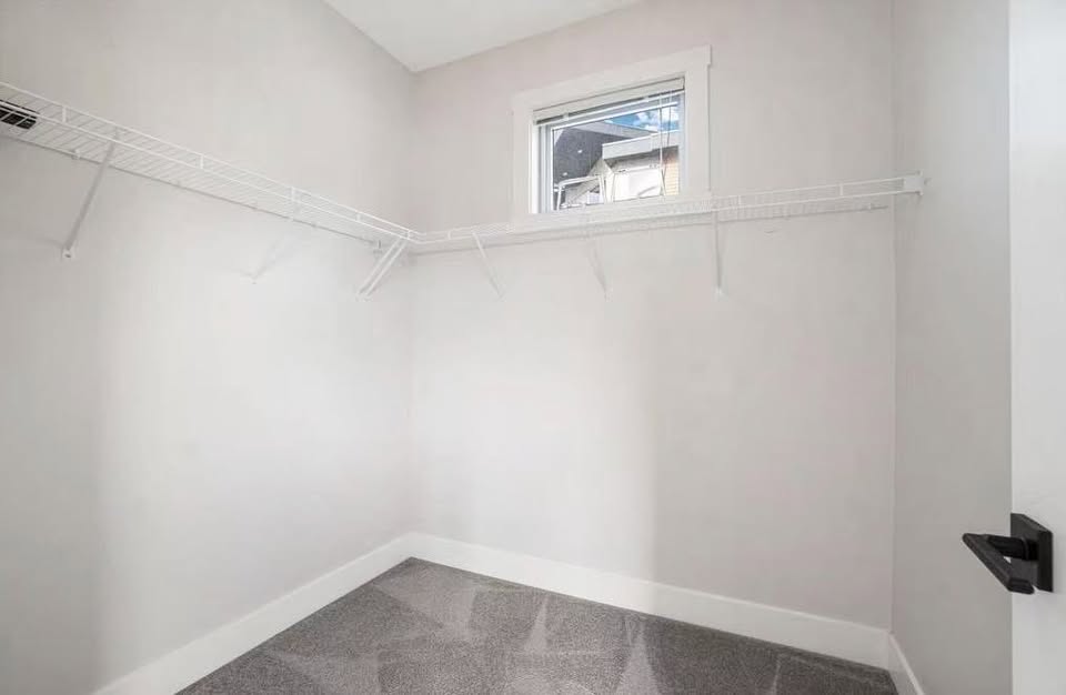 Bright walk-in closet with white walls, a small window, and wire shelving, ideal for organized storage in a Nanaimo residence.