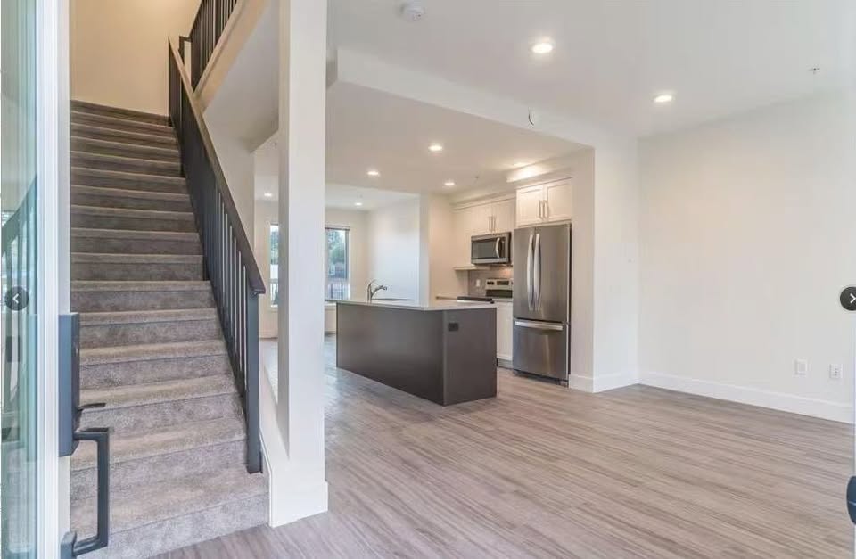 Spacious modern kitchen with stainless steel appliances and open living space at 105-308 Hillcrest Ave, Nanaimo.
