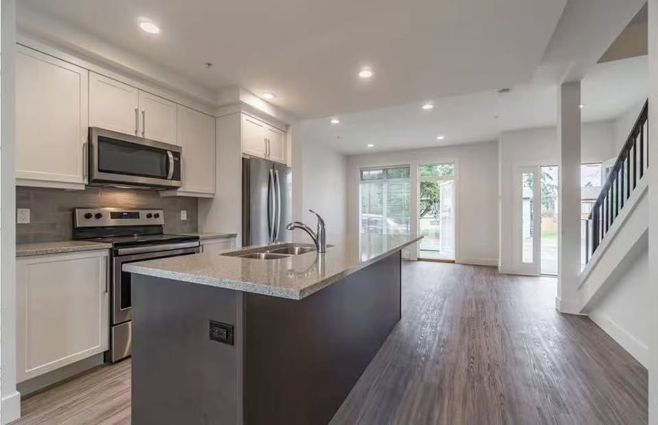 Spacious modern kitchen with white cabinets, stainless steel appliances, and an island in a Nanaimo home.