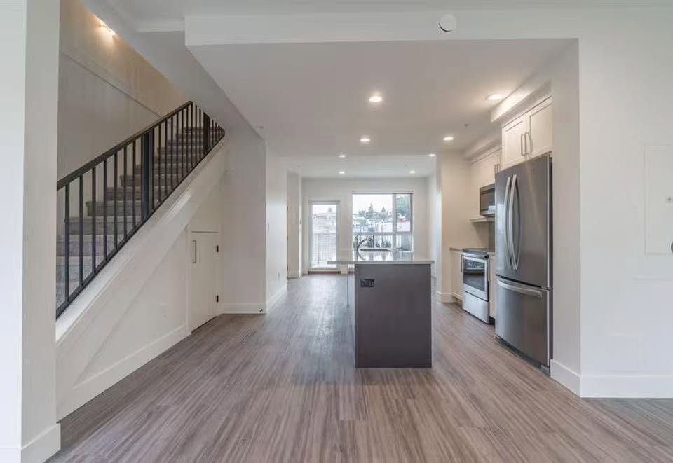 Spacious modern kitchen with stainless steel appliances, island, and open layout at 105-308 Hillcrest Ave, Nanaimo.