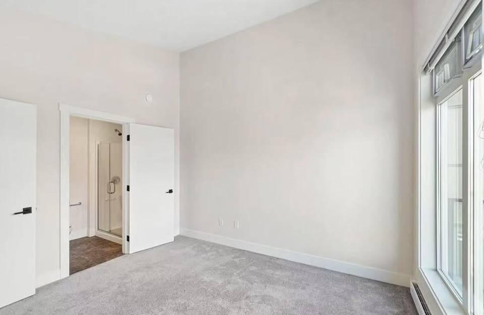 Spacious, well-lit room with large windows and neutral decor at 105-308 Hillcrest Ave, Nanaimo, showcasing modern home features.