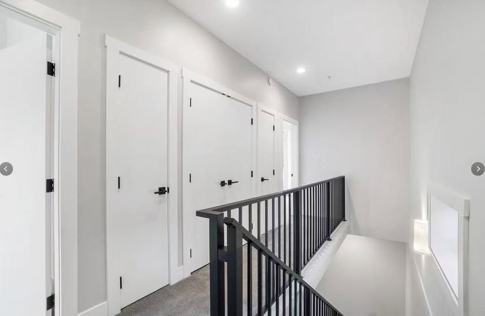 Bright, modern hallway with white doors and black railing at 105-308 Hillcrest Ave, Nanaimo, showcasing contemporary home design.