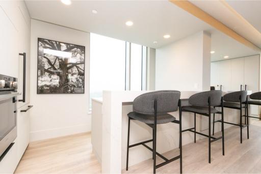 Modern kitchen with bar seating and large windows in Coquitlam property at 1409-567 Emerson St.