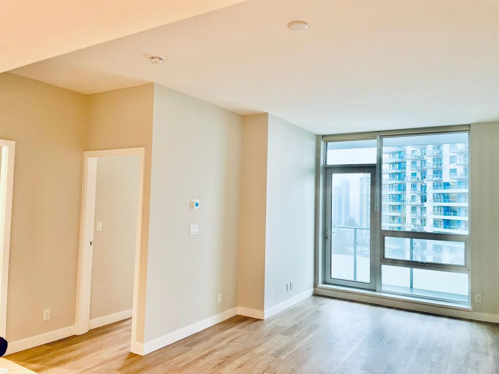 Bright, modern living room with large window view of Coquitlam high-rise buildings.