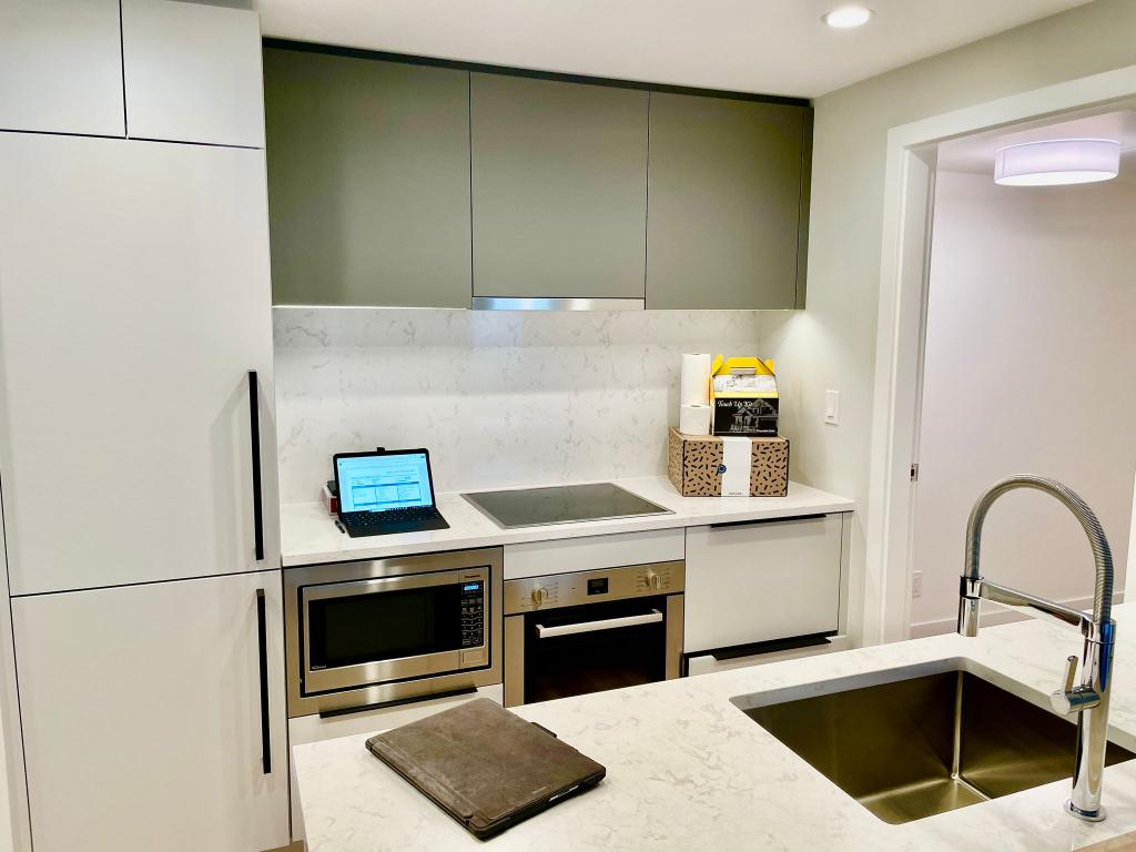 Modern kitchen with white and grey cabinetry, marble countertops, and stainless steel appliances.