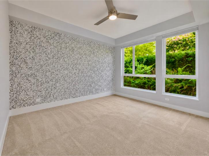 Spacious North Vancouver room with large windows and a ceiling fan, overlooking lush greenery outside, ideal for home staging or real estate listings.