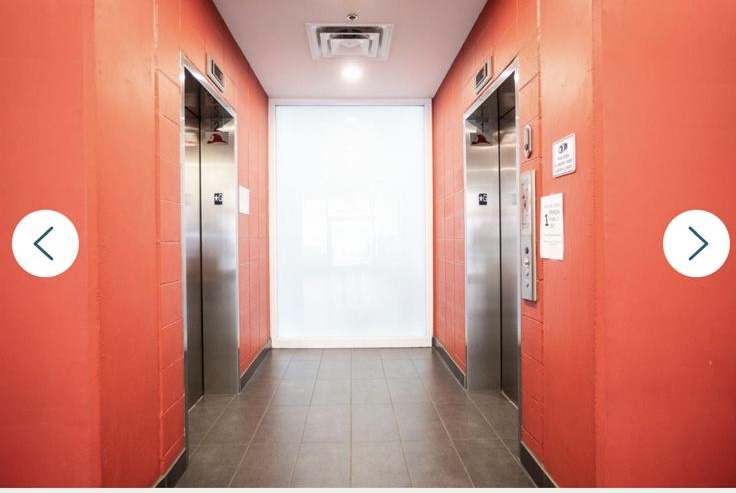 Contemporary elevator lobby with red walls and stainless steel elevators in Vancouver property.