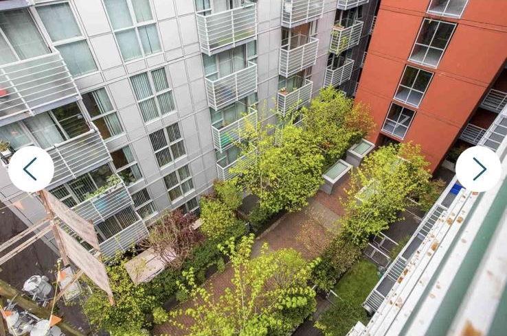 View of a courtyard with trees and pathways between modern apartment buildings in Vancouver.
