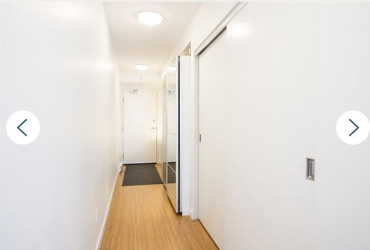 Bright, minimalist hallway in a Vancouver apartment with white walls, wooden flooring, and sliding closet doors.