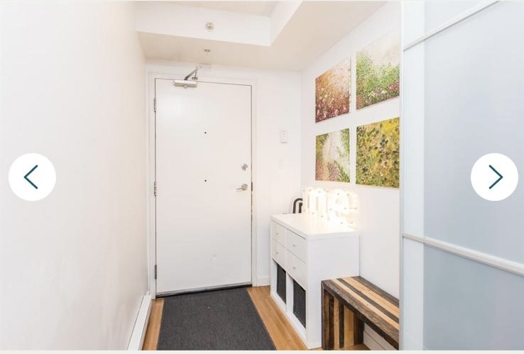 Interior view of a modern Vancouver property entrance with artwork and a shoe storage bench.