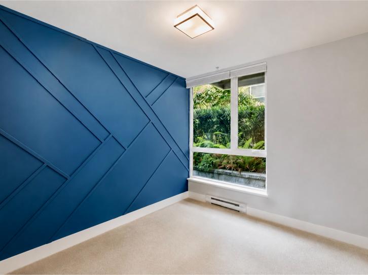 Bright interior room featuring a striking blue accent wall, large window with greenery view, and neutral carpet flooring, ideal for a North Vancouver home.