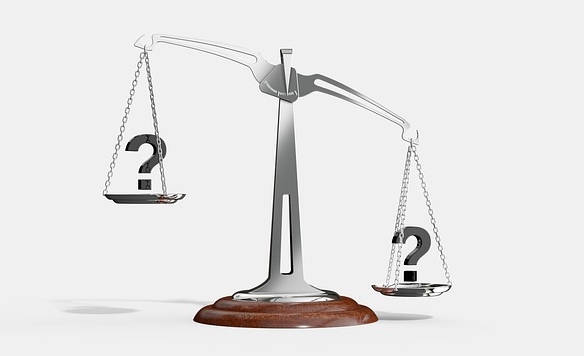 Scales with question marks on each side, symbolizing uncertainty or comparison